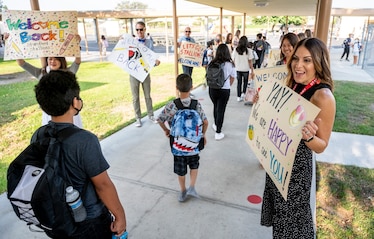 Third-grade teacher Becky Maturo (right) welcomes students back to in-person learning at Stanford Elementary School in Garden Grove, California. Both children and instructors will be wearing masks inside classrooms.
