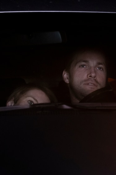 a man and woman in there car watching a movie at a drive in theatre