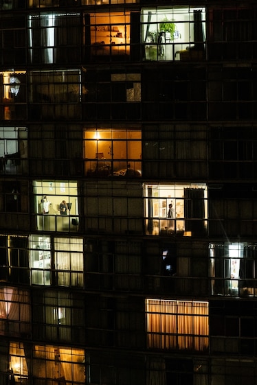 an apartment building at night, people can be seen from their windows