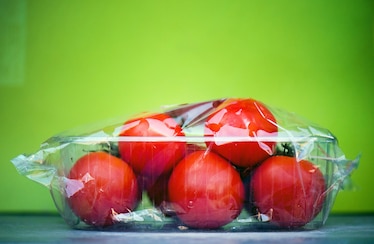 red tomatoes wrapped in translucent plastic in a green kitchen