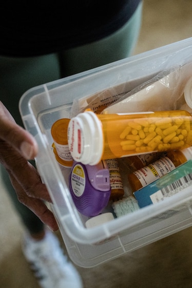 A small plastic bin full of various bottles of pills.