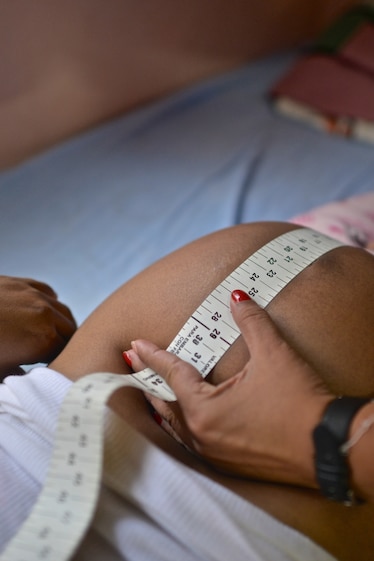 A doctor uses a measuring tape to measure the abdomen of a pregnant woman.